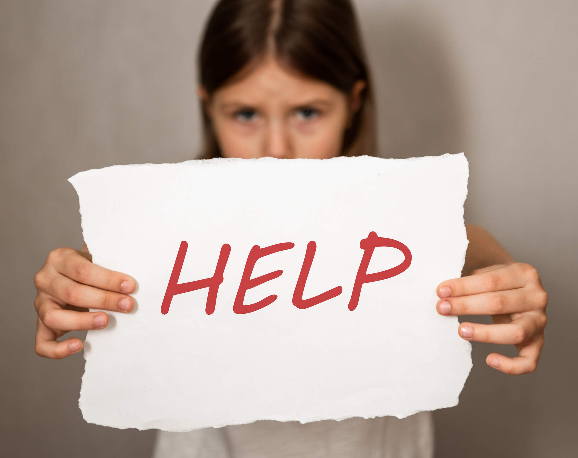 Conceptual image of a sad dejected little girl standing holding a help sign
